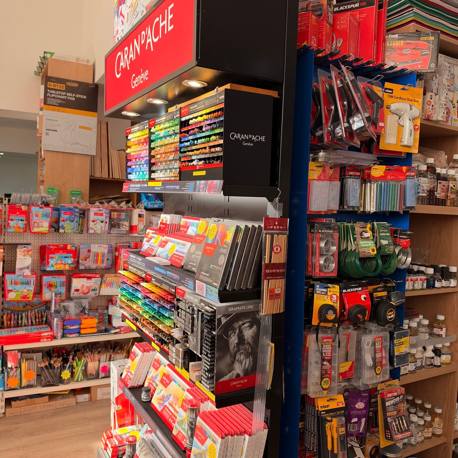 A Caran d’Ache stand of colouring pencils and pastels, with children’s colouring sets, brushes and art mediums on the shelves behind.