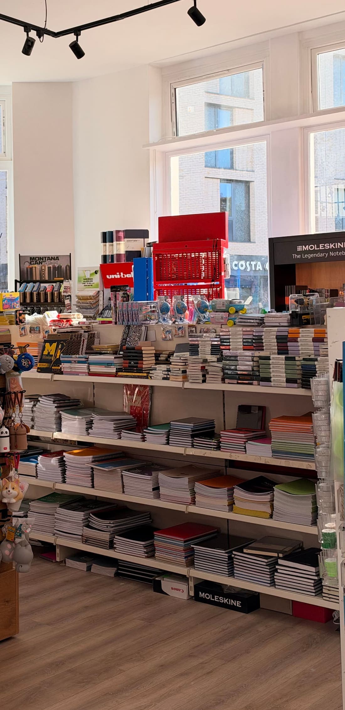 Inside the shop: shelves of notebooks and exercise books, with Moleskine and Leuchtturm1917 displays and a uni-ball pen stand by the window.