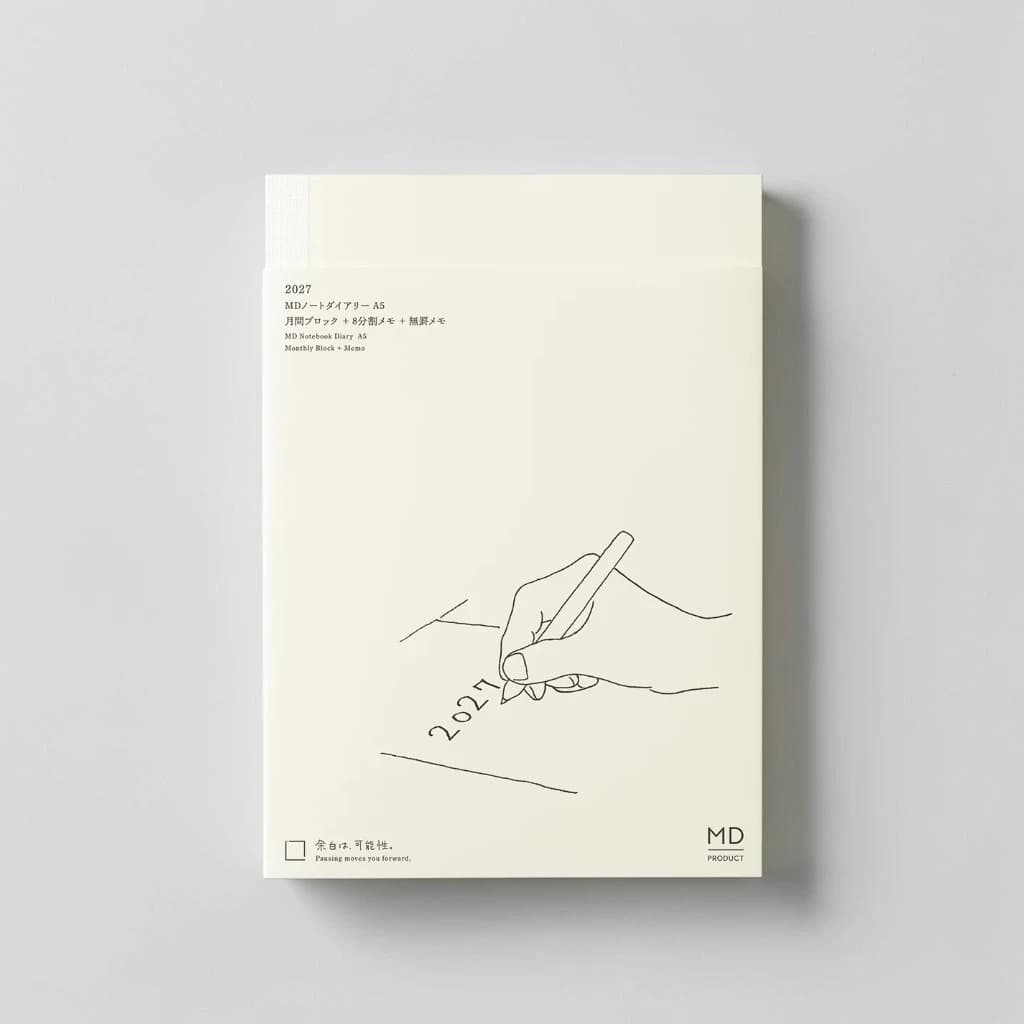The MD Notebook Diary 2027 A5 in its cream cover, with a line drawing of a hand writing 2027.